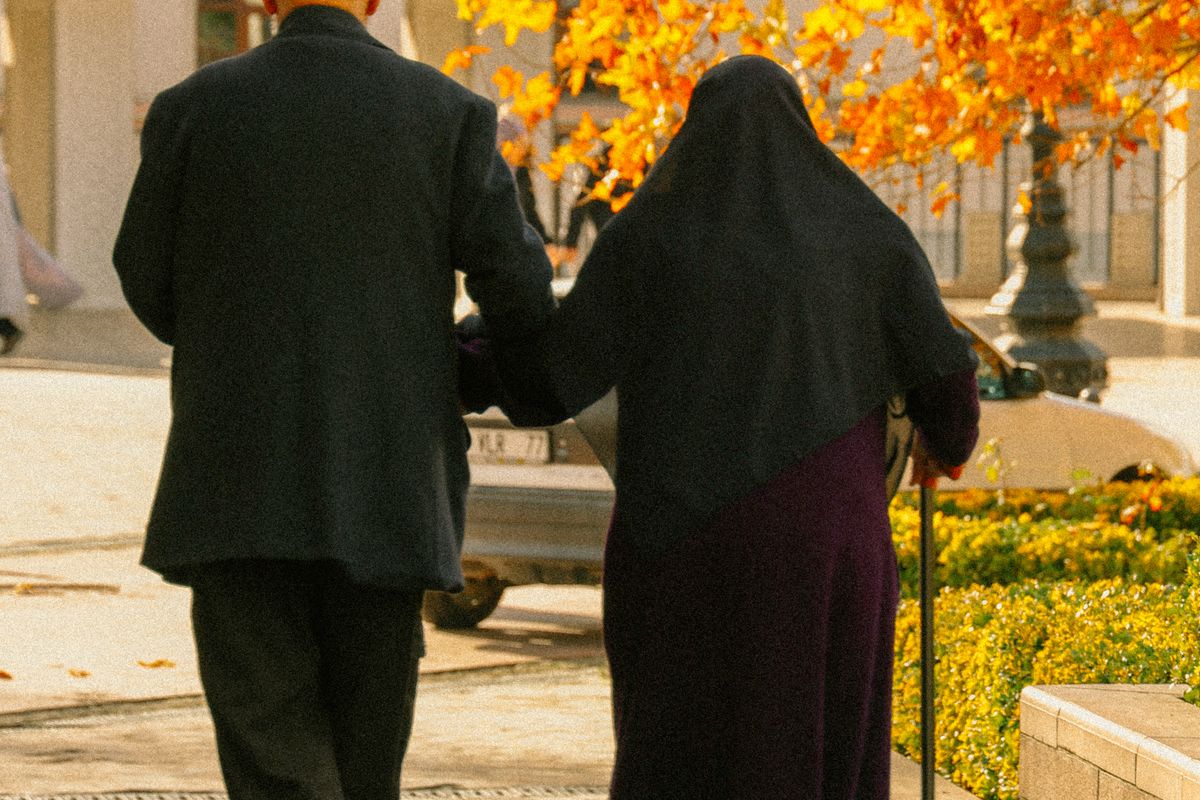 Older couple walking together in a park in autumn